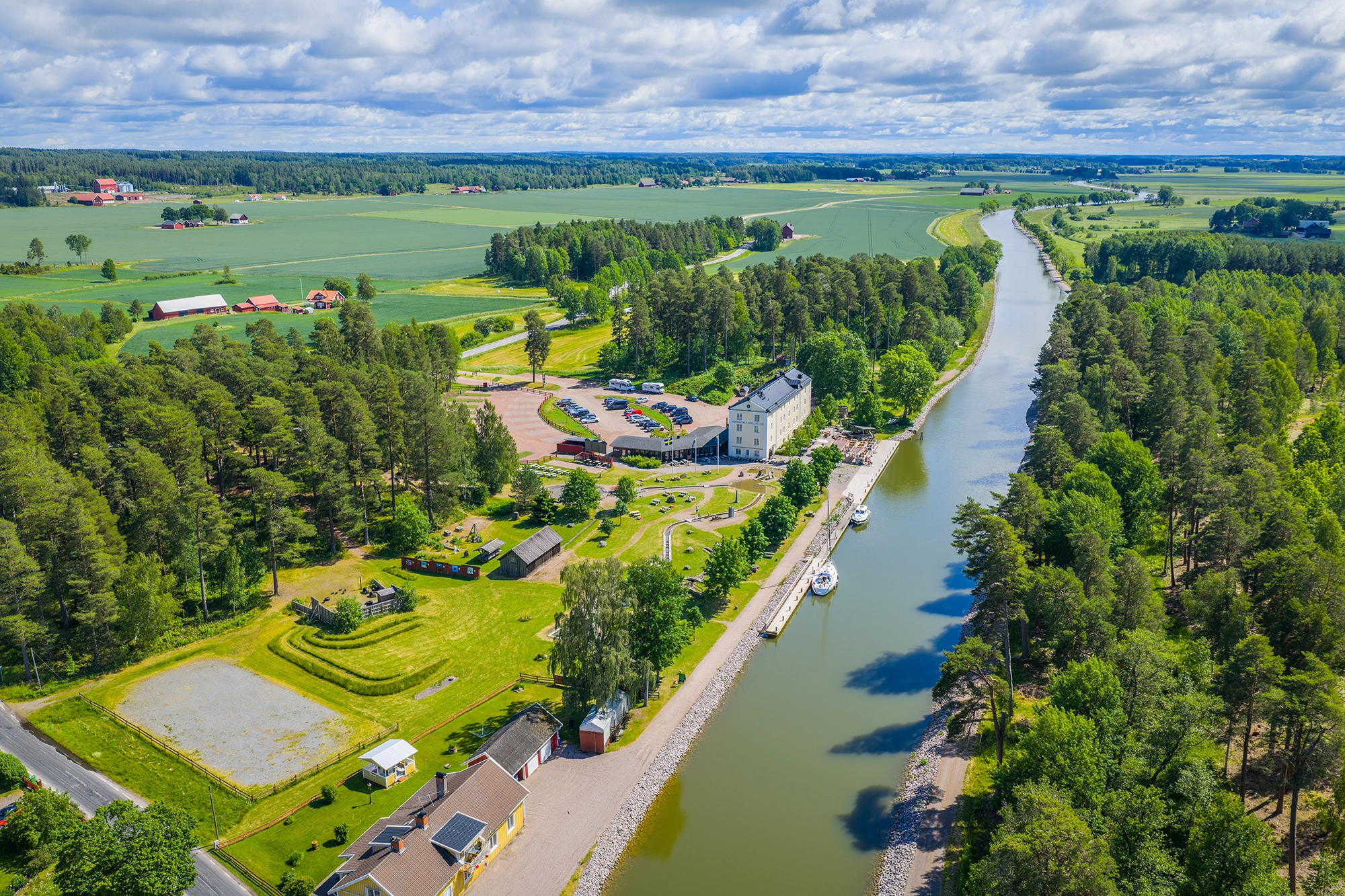 Göta kanal med båtar och Norrqvarns grönskande slussområde från luften